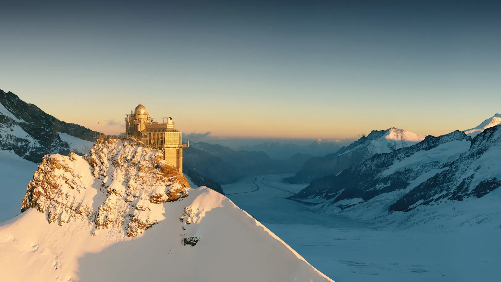 La piattaforma panoramica Sphinx sullo Jungfraujoch al tramonto, con un paesaggio glaciale sullo sfondo.
